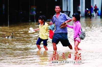 樂(lè)昌市政府前和街道被水浸,一位家長(zhǎng)帶著孩子涉水而行?！　」攘⑤x童銅韶朱裕超攝