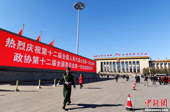 3月4日，北京晴空萬里，武警從北京天安門廣場大型顯示屏前走過。3月5日上午，十二屆全國人大一次會(huì)議將隆重開幕。中新社發(fā) 劉忠俊 攝